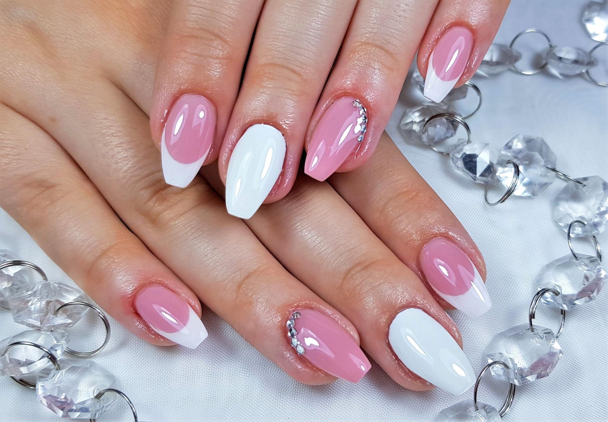 Pink and white acrylic full set with a glossy French finish and a small gem accent — real work by US Nails